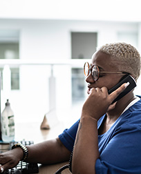 woman in scrubs on the phone sitting at a desk.