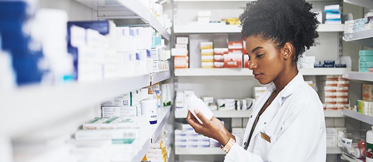 pharmacist reading prescription bottle in pharmacy