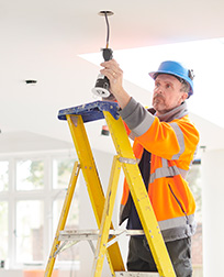 electrician on ladder installing lights in home