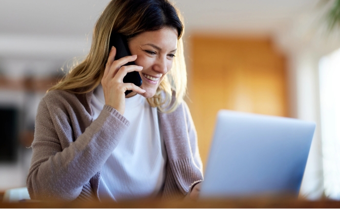 woman on phone working on laptop.