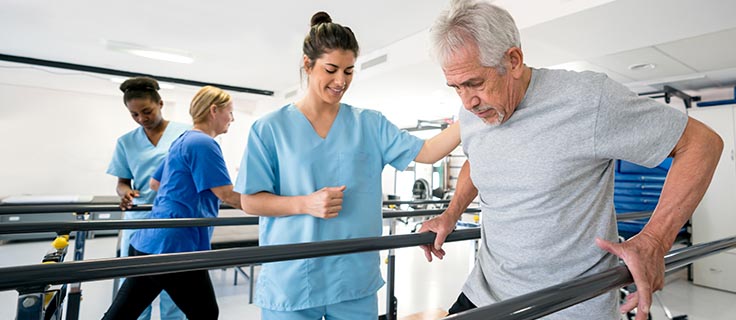 physical therapist helping patient use walking bars.